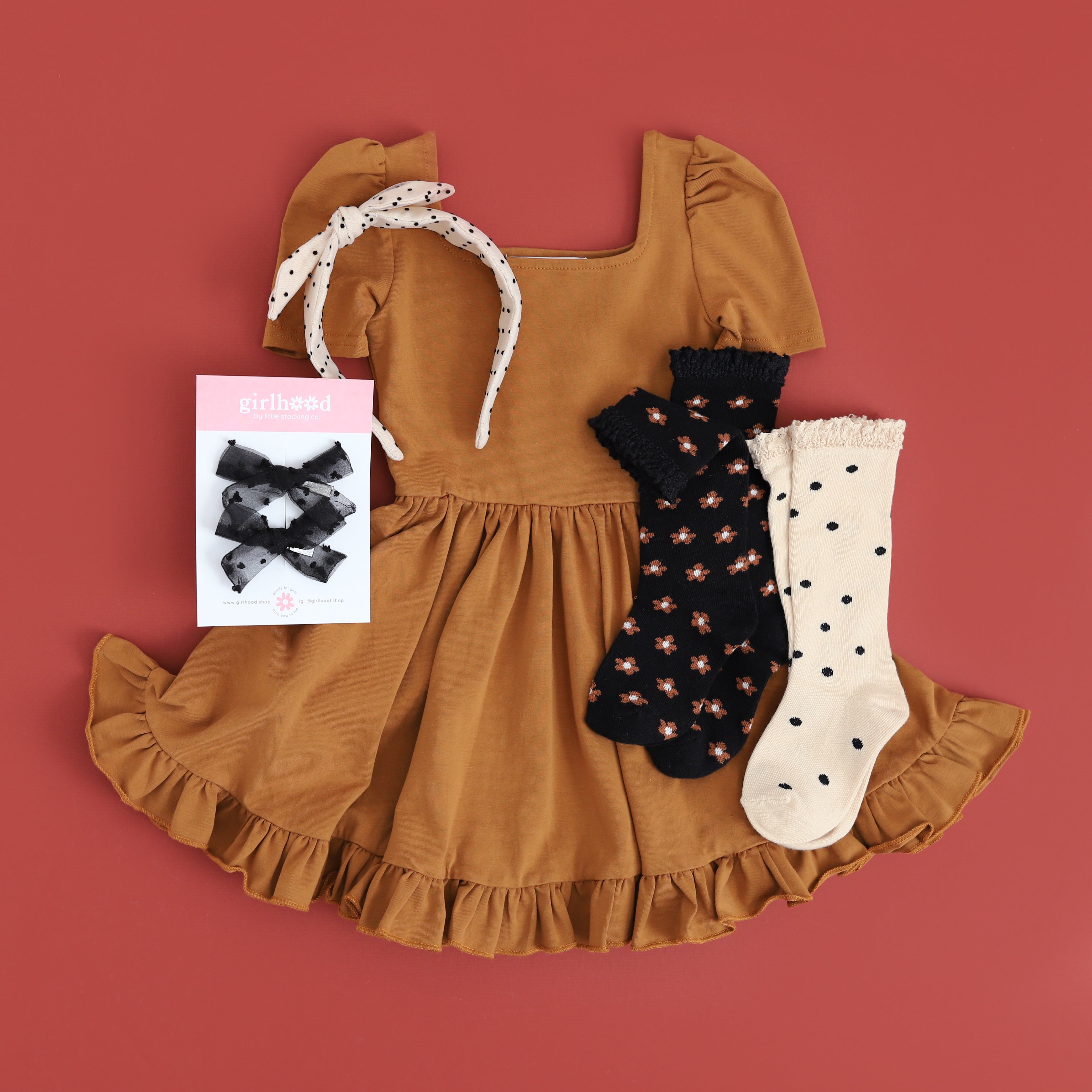 flatlay of girls outfit of pecan twirl dress, black floral socks, and polkadot knee highs