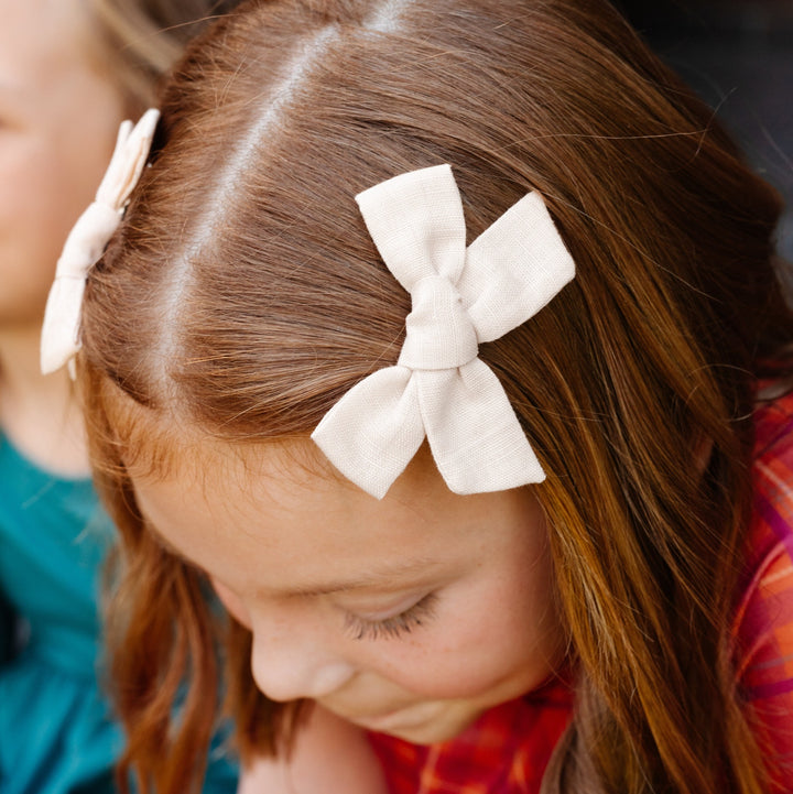 little girl with vanilla linen hair bows clipped on each side of hair