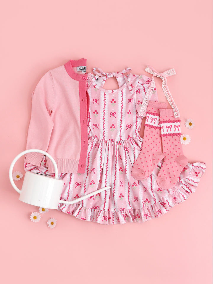 flatlay of girls easter outfit with pink spring wallpaper print with pink flowers and bows and matching pink accessories