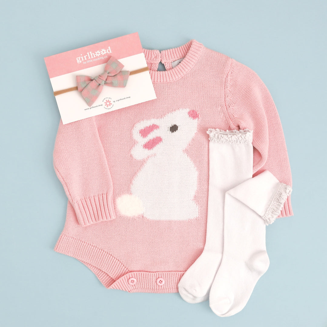 flatlay of pink baby romper with white bunny, white knee high socks and pink and aqua gingham bow