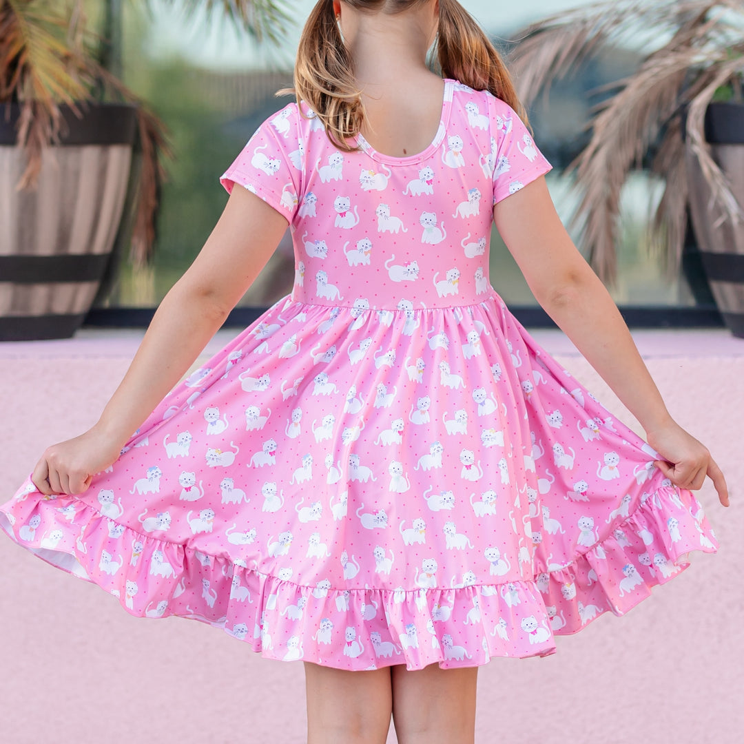 back view of girl in pink short sleeve twirl dress with white kitten print