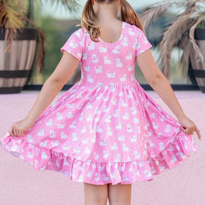 back view of girl in pink short sleeve twirl dress with white kitten print