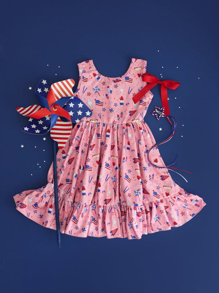 flatlay of girls pink 4th of july sleeveless twirl dress and matching bows
