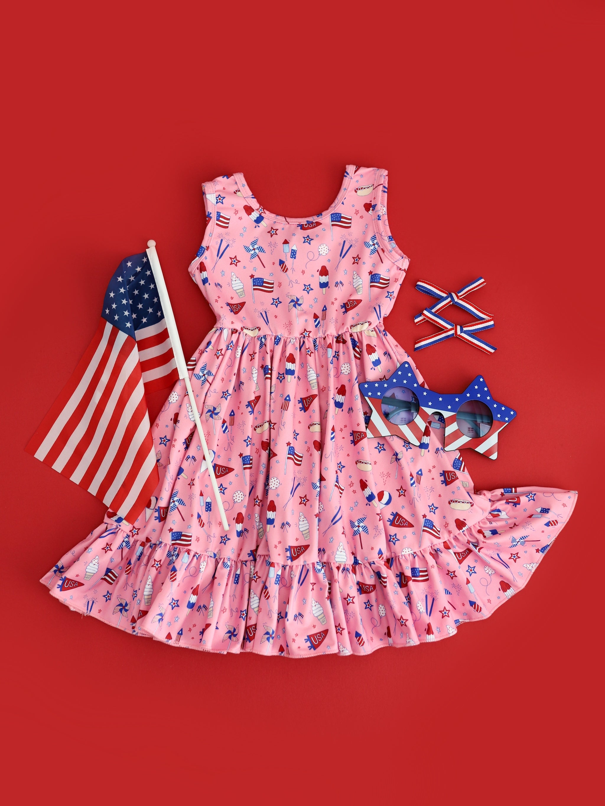 flatlay of girls pink 4th of july sleeveless twirl dress and matching accessories