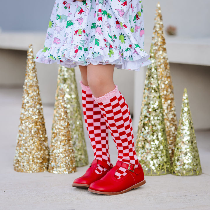 little girl wearing pink and red checker knee high socks with christmas dinos dress
