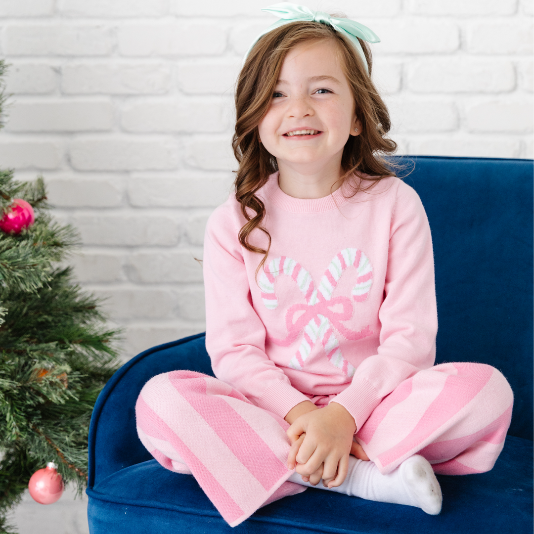 girl in pink stripe knit pants and pink candy cane christmas sweater