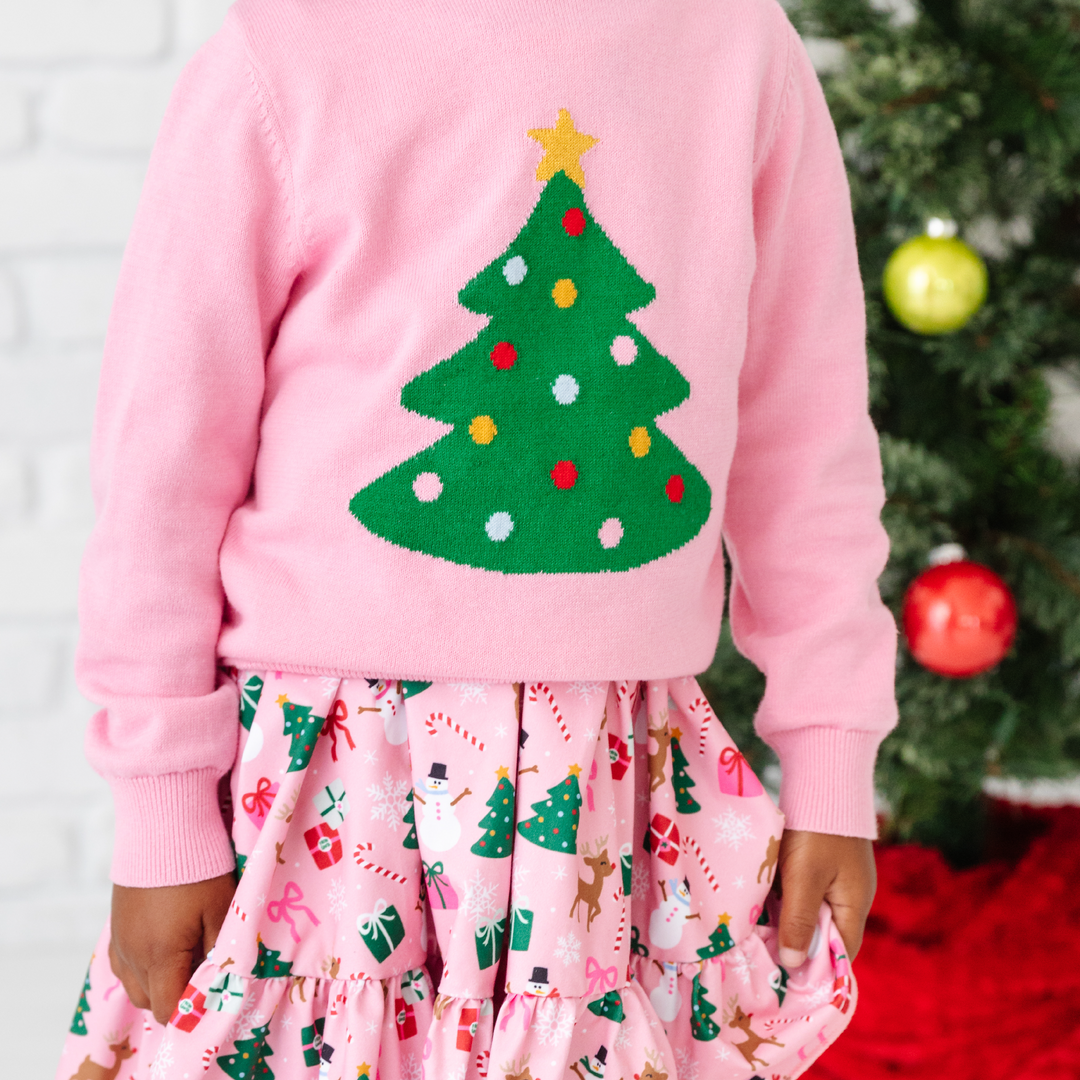 girl in pink sweater with christmas tree and christmas party dress