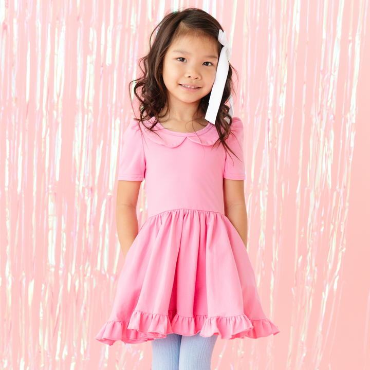 little girl in spring pink cotton twirl dress with light blue cable knit tights and white satin bow