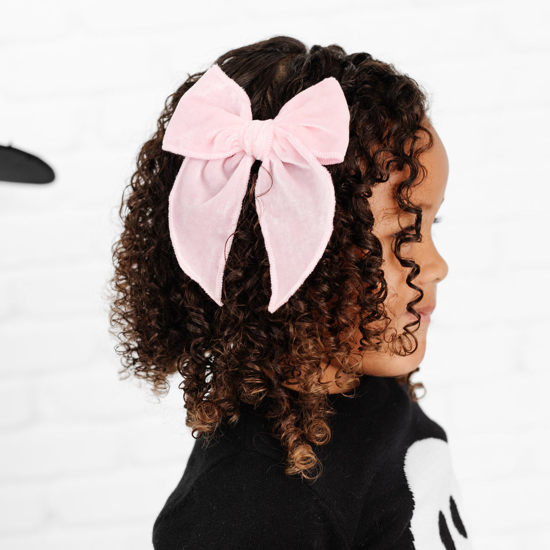 little girl wearing light pink velvet hair bow