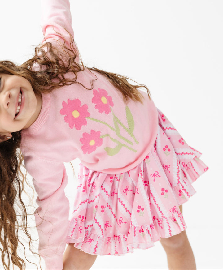 girl playing in twirl dress with pink bow and flower wallpaper print and matching bouquet pullover sweater