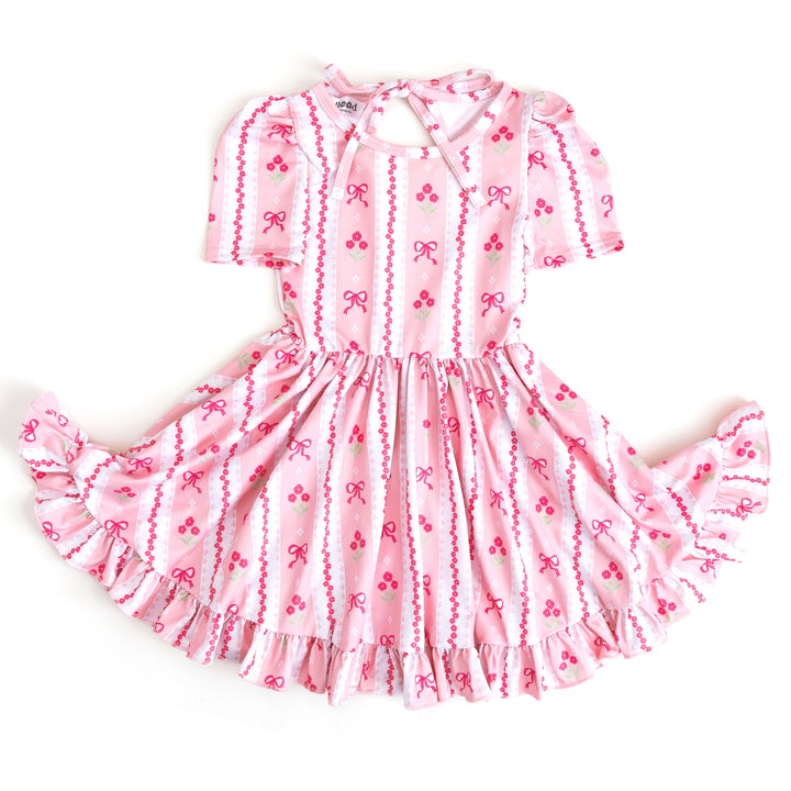 girl's short sleeve twirl dress in pink with wallpaper print featuring bows and flowers for Easter 