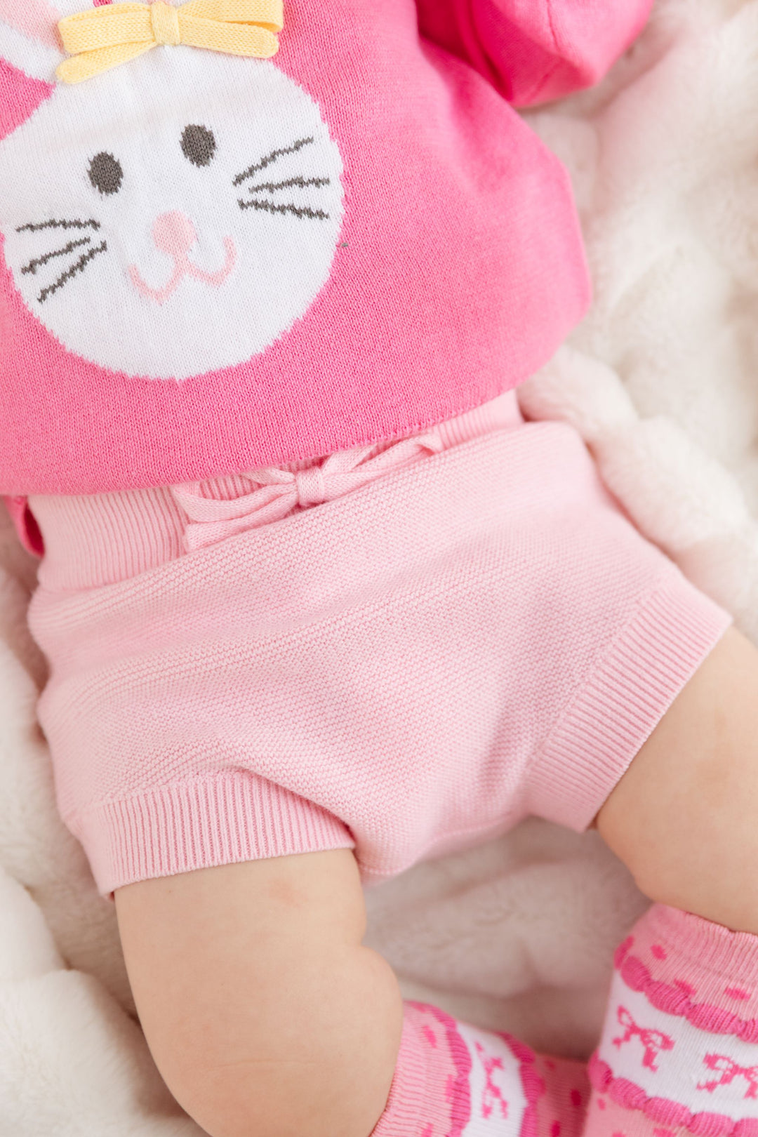 baby girl in pink knit sweater with bunny design and matching light pink bloomers for Easter