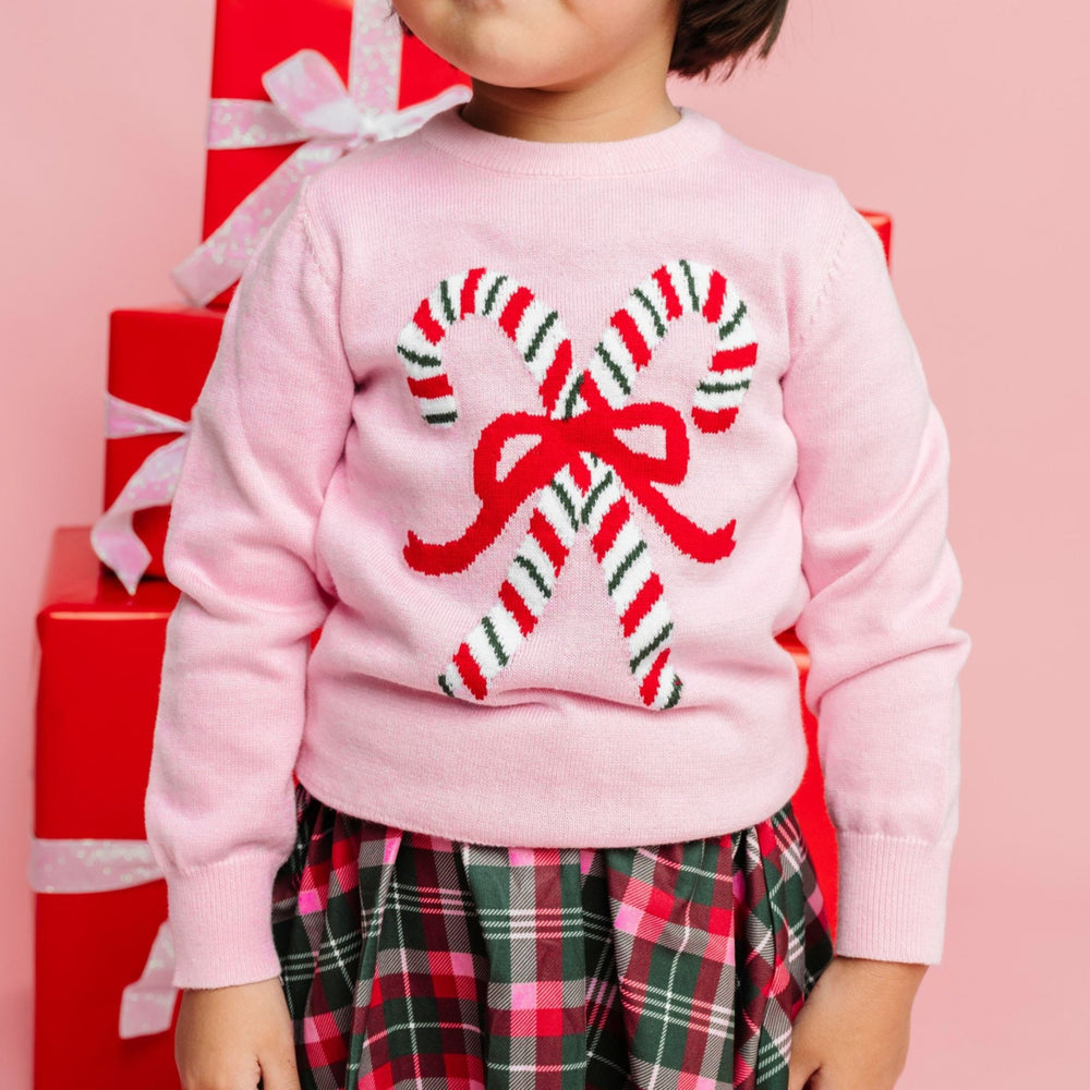 sweater close up of little girl in pink knit pullover sweater with red, green and white striped candy canes and matching Christmas plaid skirt