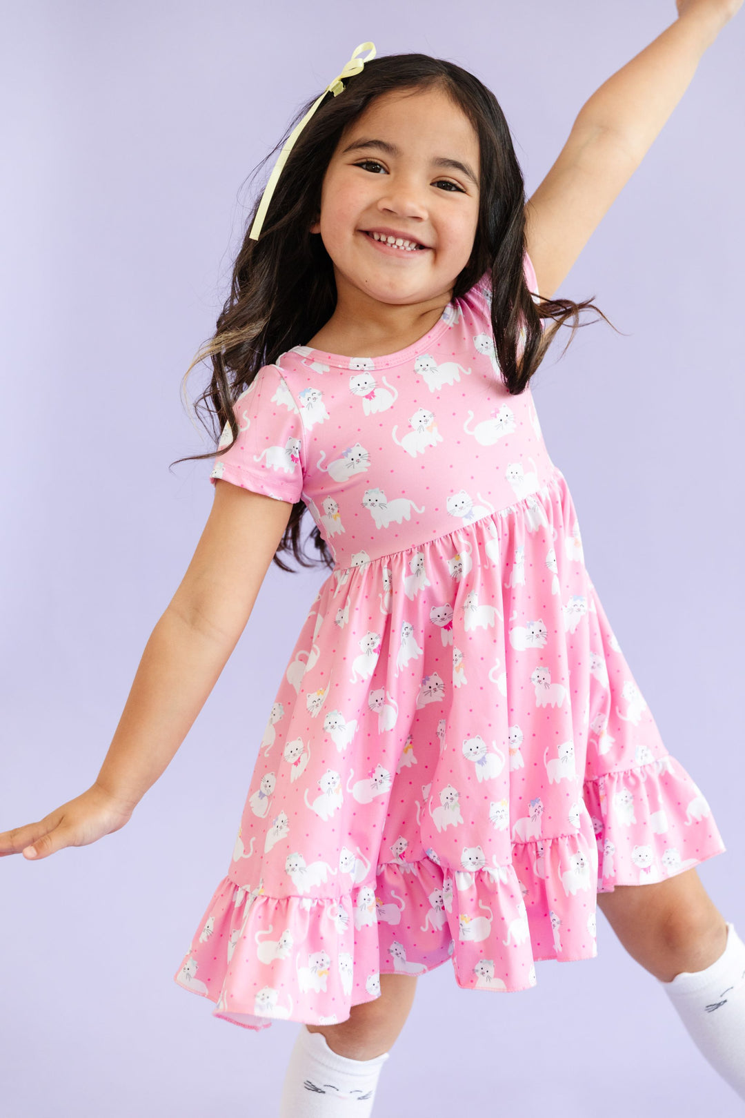 little girl posing in pink drfess with white kitten print and matching white knee-high socks with cat ears and printed whiskers