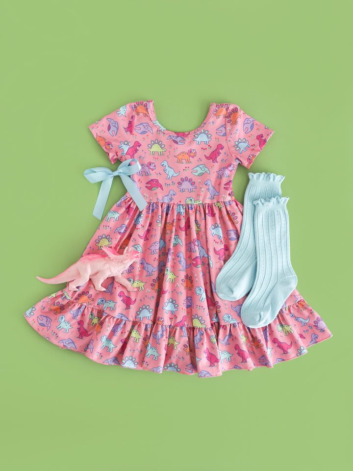 styled flat lay of girl's short sleeve pink twirl dress with bright pastel dinosaurs and matching robin egg blue accessories