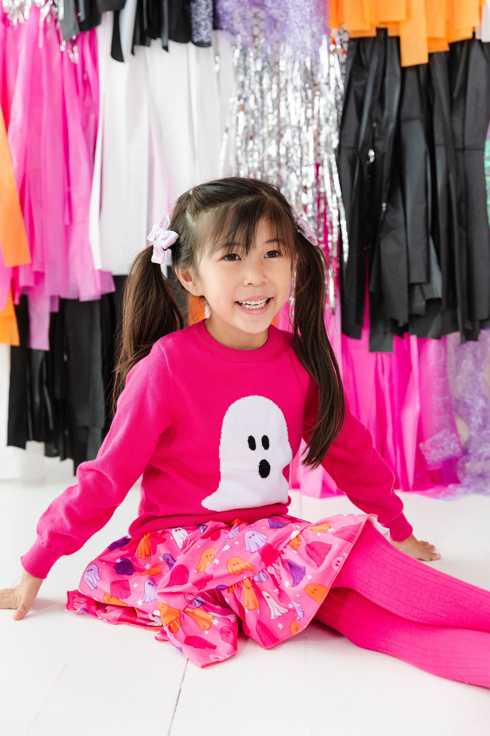 girl wearing bright pink ghost sweater with pink ghosts dress