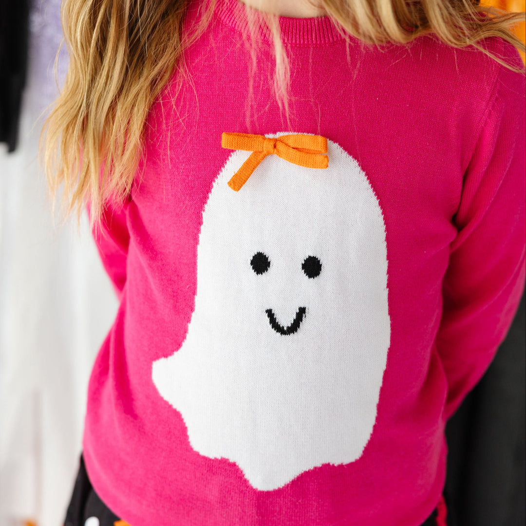 girl wearing a bright pink sweater with a ghost on it
