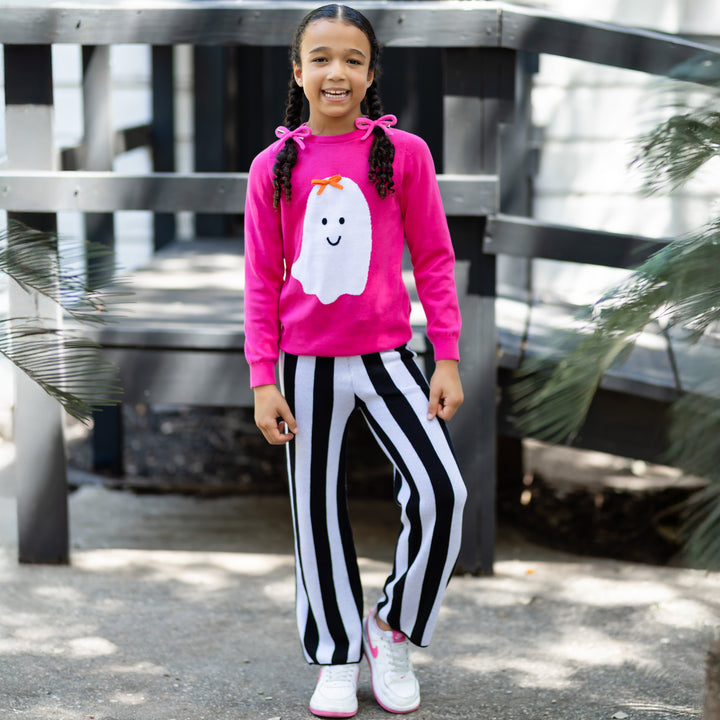 girl in bright pink cotton knit sweater with white ghost wearing orange 3-D knit bow paired with black and white striped sweater pants