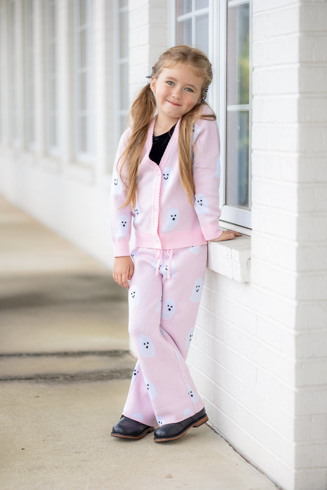 little girl in matching light pink knit cardigan and sweater pants with white ghost design layered over valvet top for Halloween