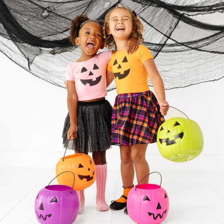 little girls in pink and orange tops with pumpkin faces and coordinating 
