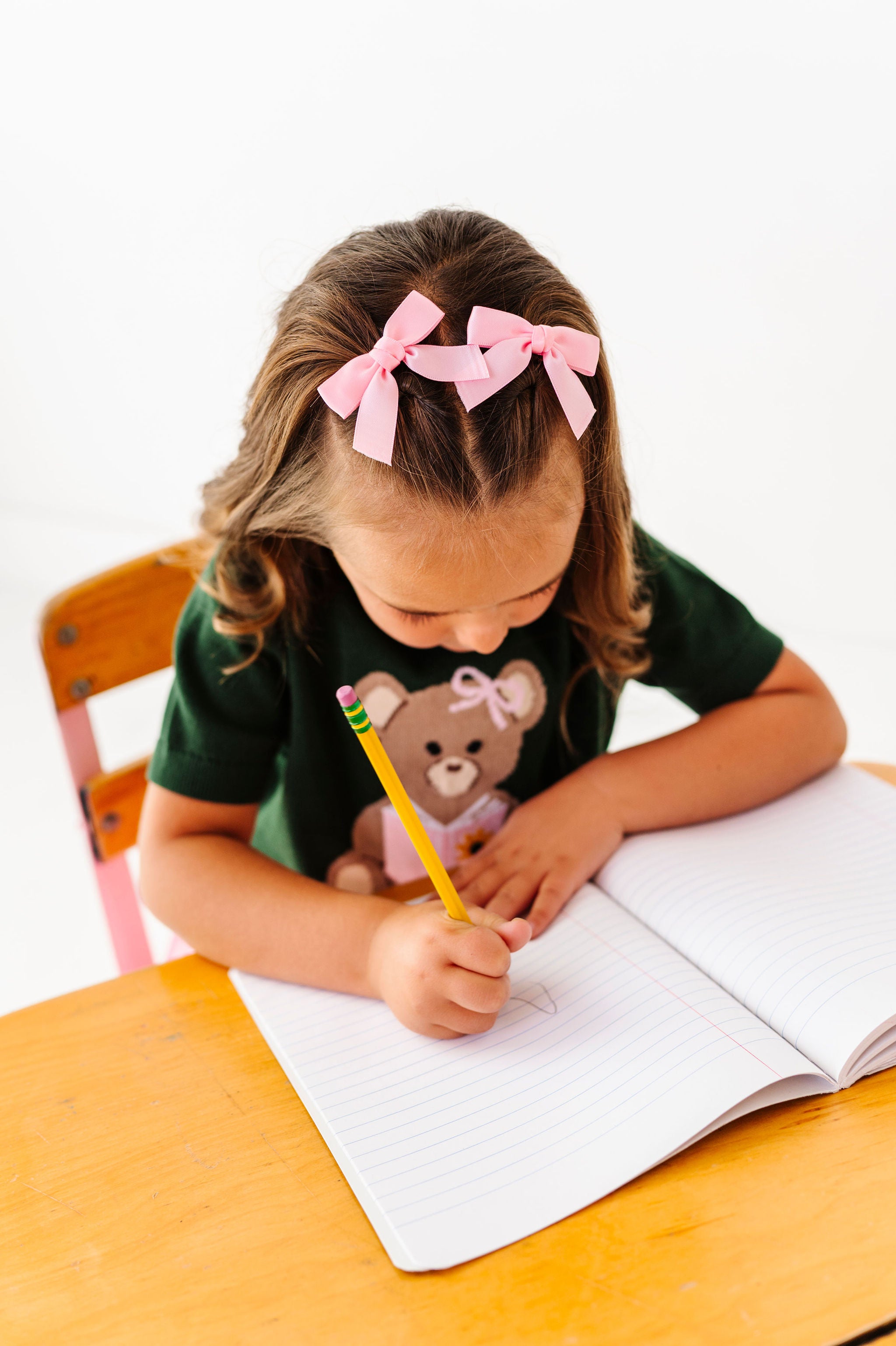 girl wearing pink satin pigtail hair bows with teddy bear sweater