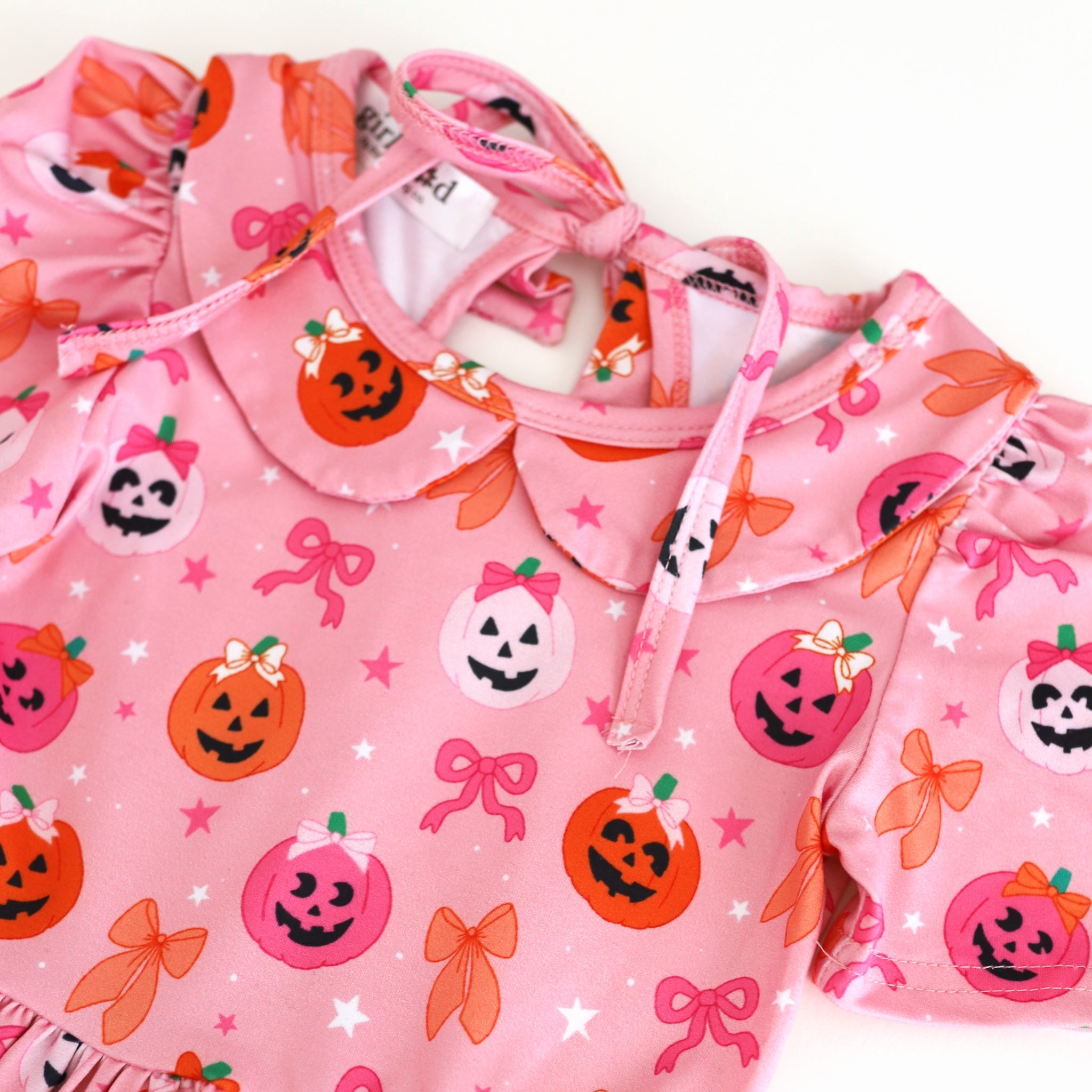 print close-up of pink collared twirl dress with pink and orange pumpkins wearing bows