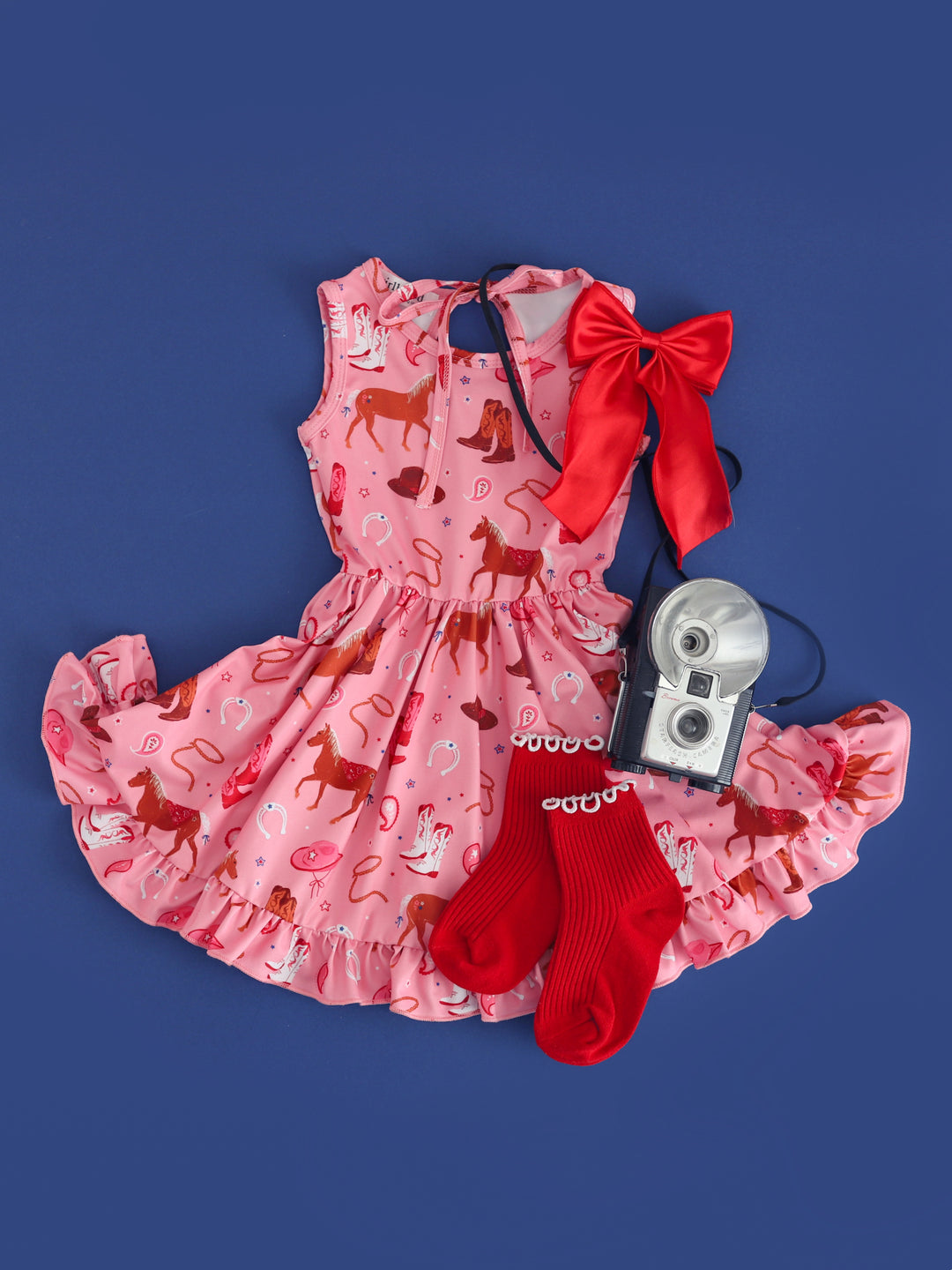 girls pink tank dress with rodeo themed print paired with red midi socks and red satin hair bow
