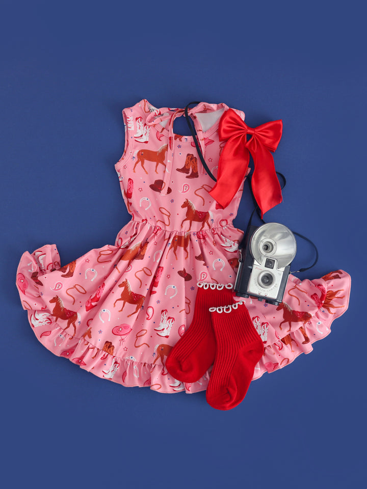 girls pink tank dress with rodeo themed print paired with red midi socks and red satin hair bow