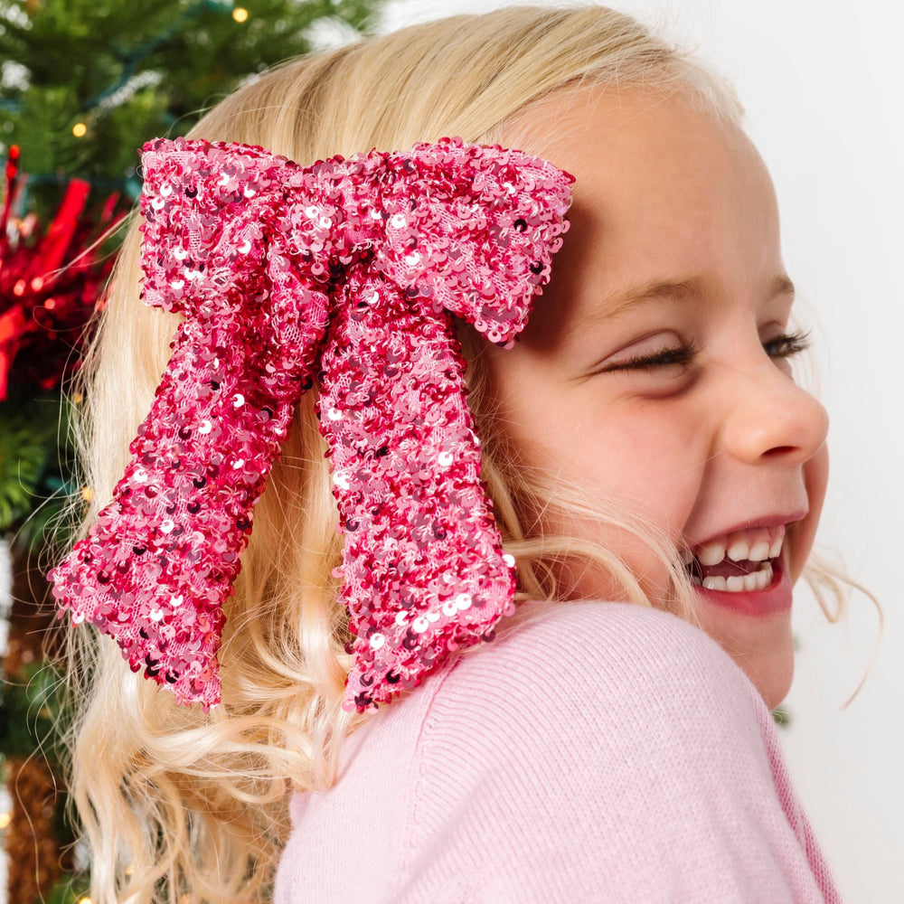 little girl in pink Christmas outfit with pink sparkly sequin hair bow on clip