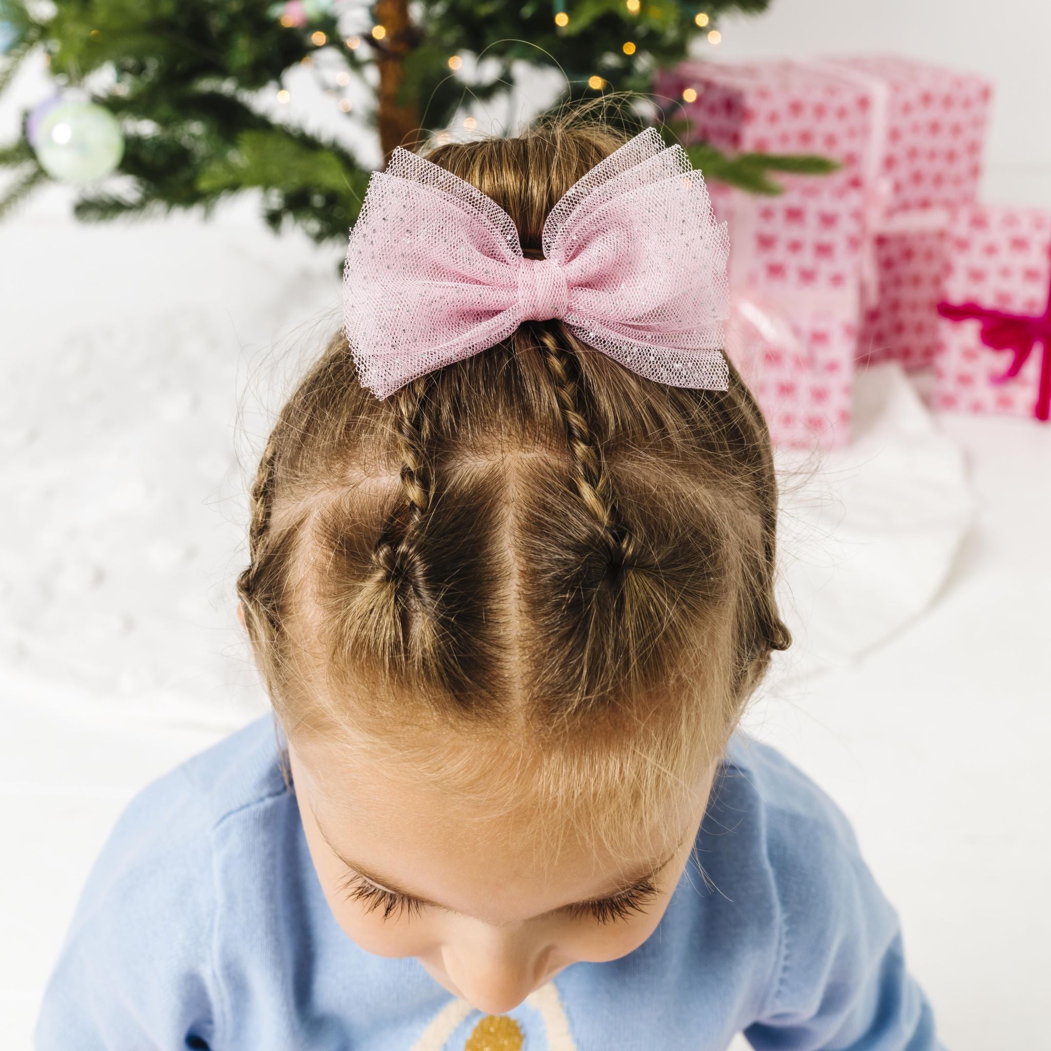 little girl in front of Christmas tree in pink tulle hair bow with sparkles to match blue ballerina sweater