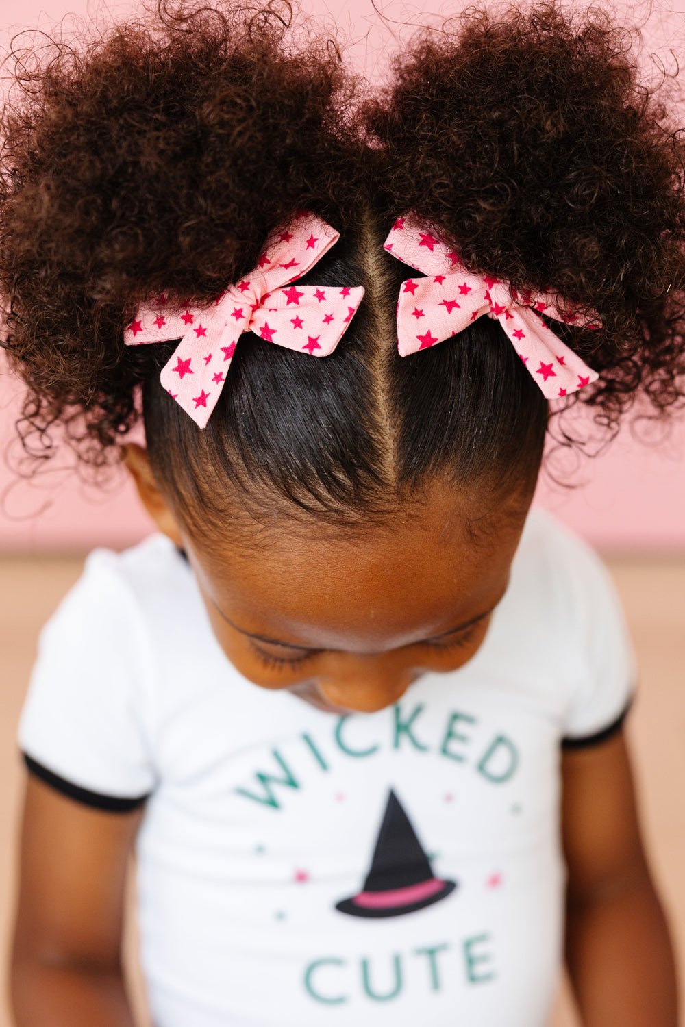 little girl with pink pigtails on clips with dark pink star print and matching Wicket Cute tee