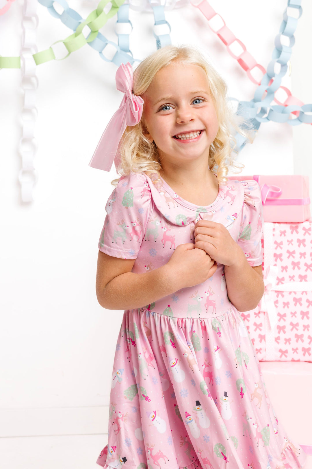 little girl wearing pink winter wonderland inspired twirl dress with collar paired with light pink satin bow on clip for Christmas