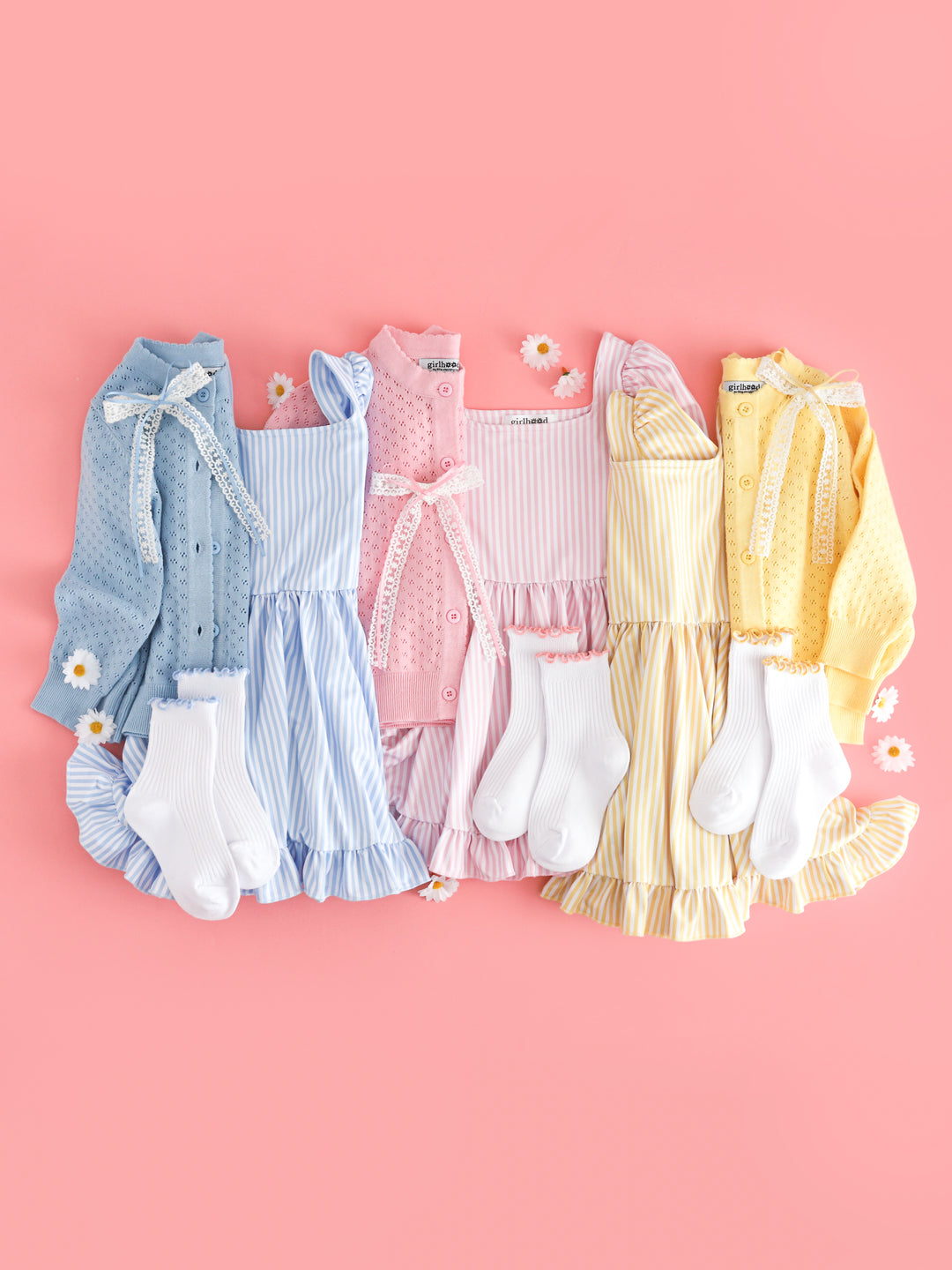 flat lay of girls' pastel pinstripe print twirl dresses in blue, pink and yellow with matching pointelle cardigans and accessories
