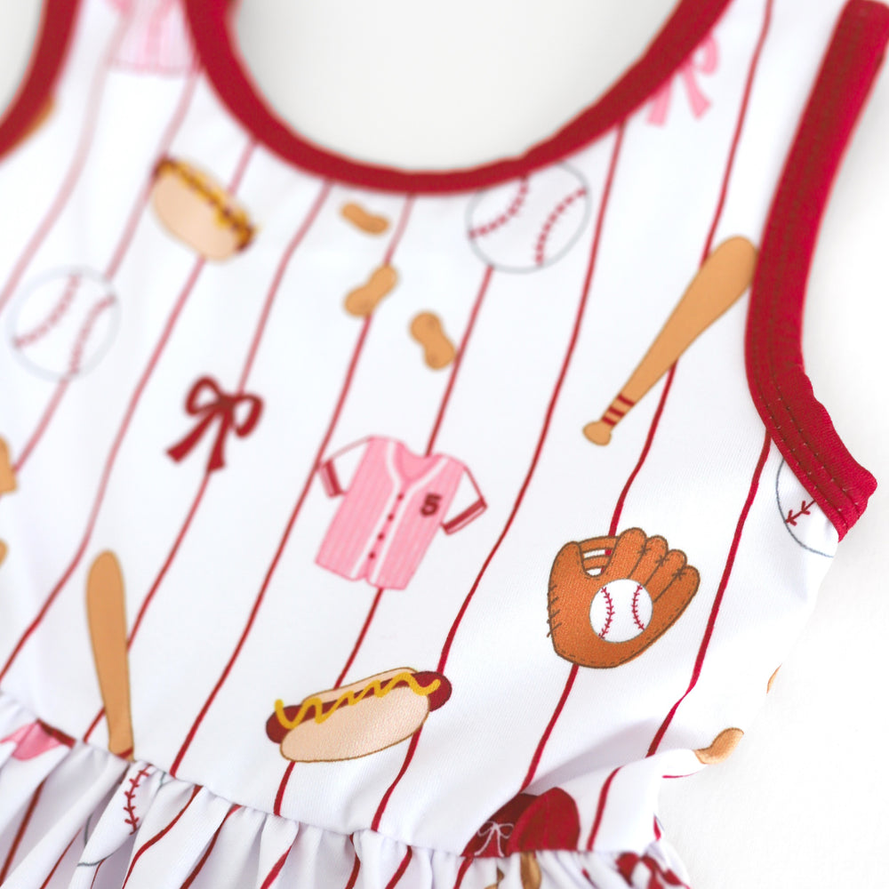 closeup of girls' baseball themed print featuring, pink jerseys, baseballs, bats, hot dogs, peanuts and bows