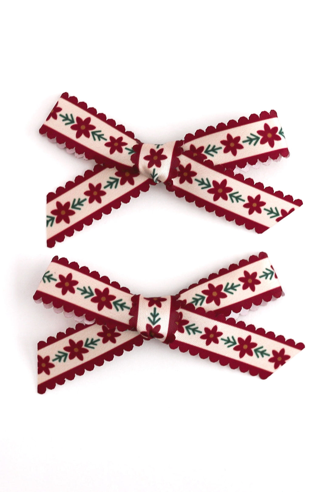 vanilla scalloped ribbon pigtail bows with crimson red poinsettia design and crimson scalloped edges shown on white background