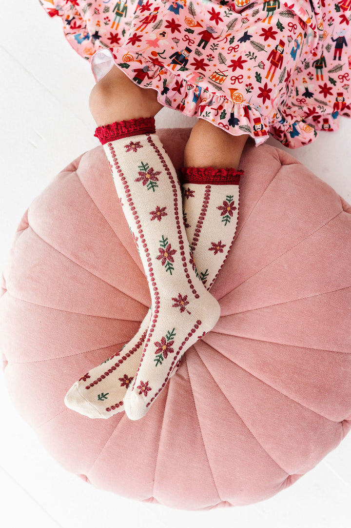 girl wearing poinsettia knee high christmas socks with matching Nutcracker themed dress