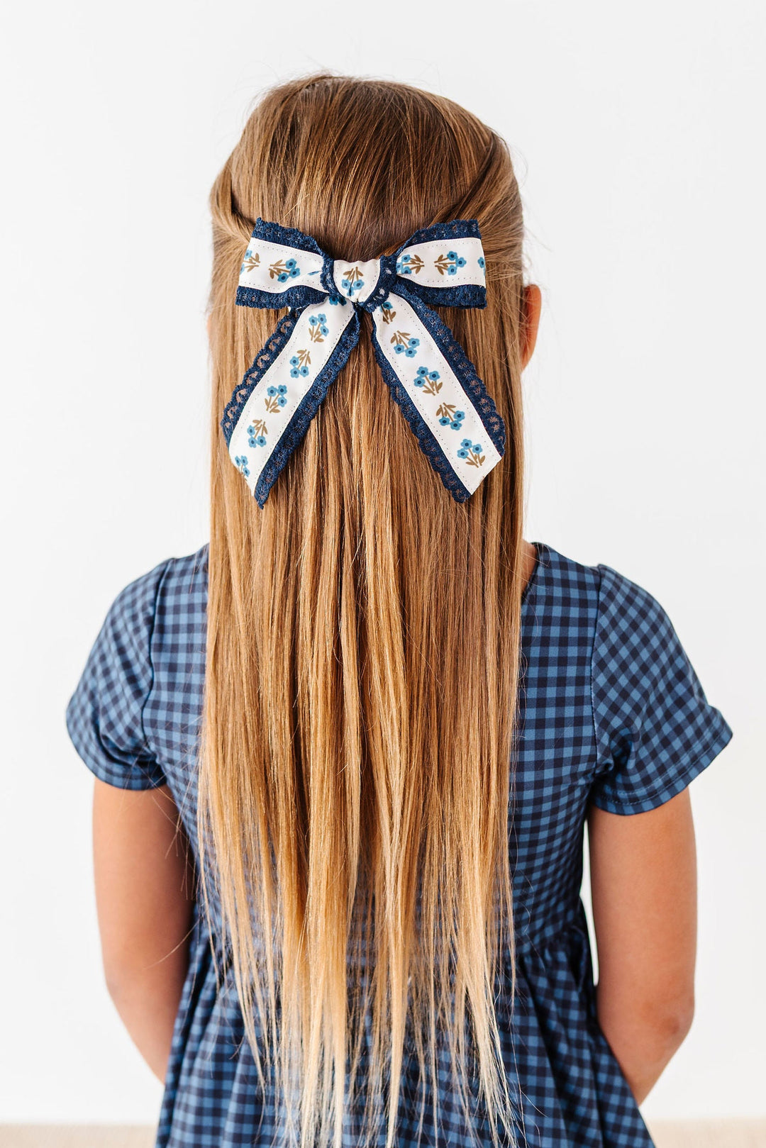 navy floral lace hair bow in little girls hair with matching navy blue gingham dress