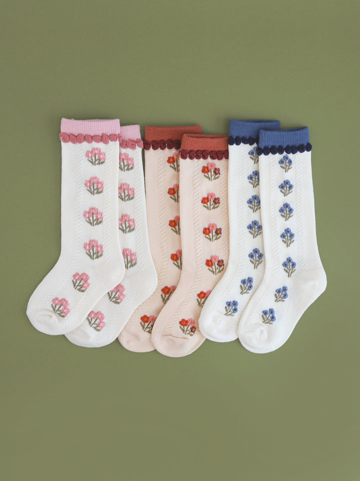 flat lay of girls' fall floral knee socks in shades of ivory and vanilla with fall pink, rust and blue colors palettes