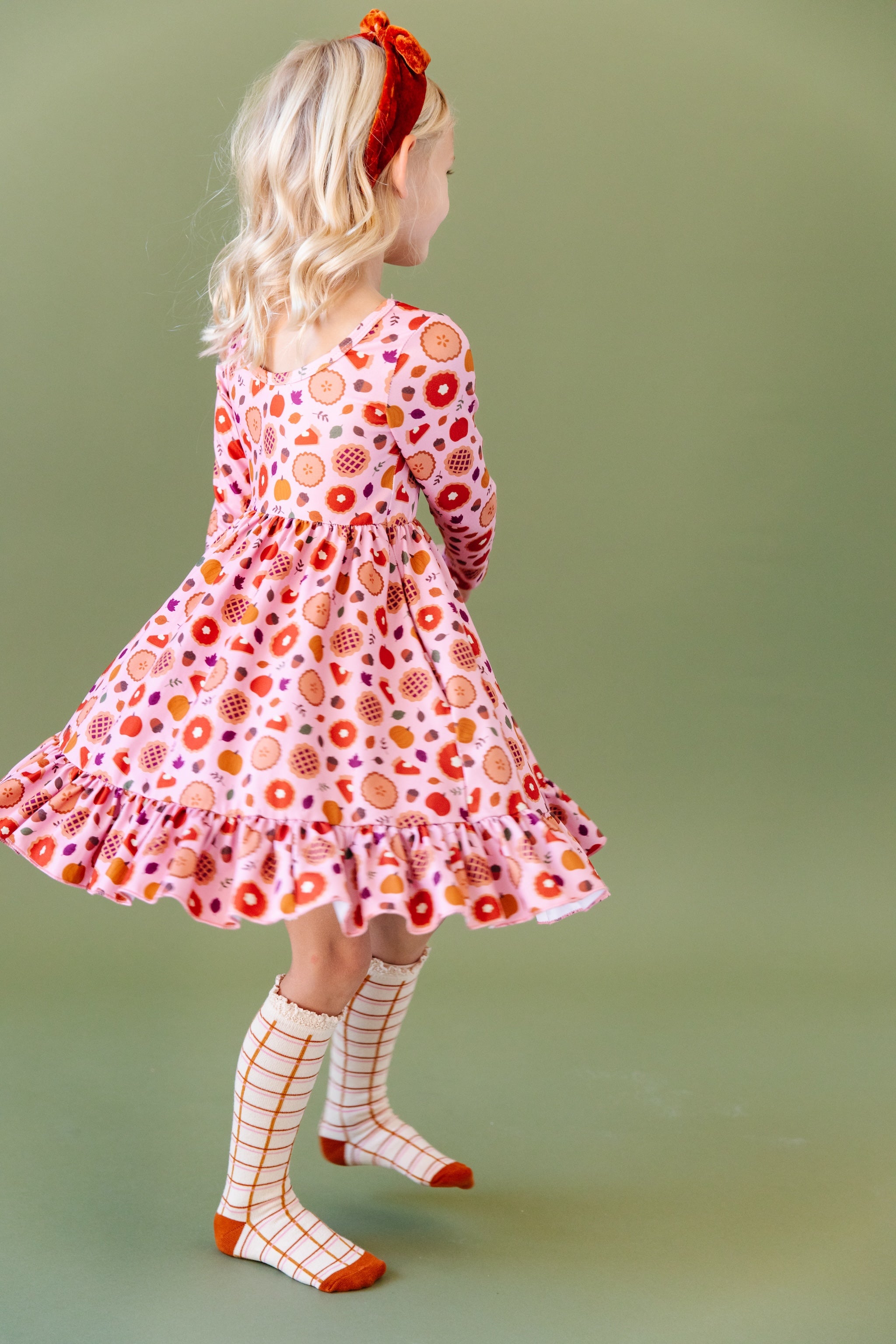 girl twirling in pumpkin pie dress and harvest grid socks