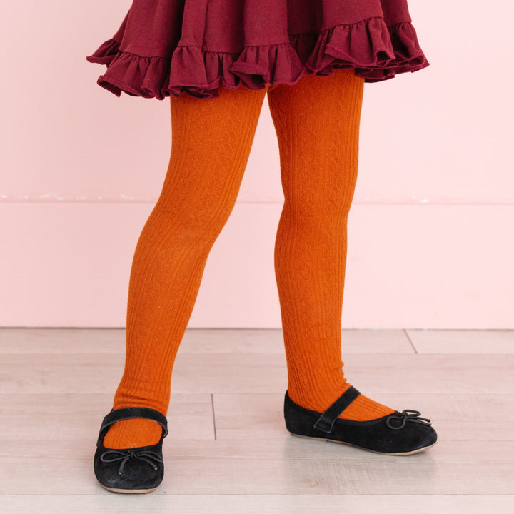 girl wearing fall orange pumpkin spice cable knit tights and black shoes