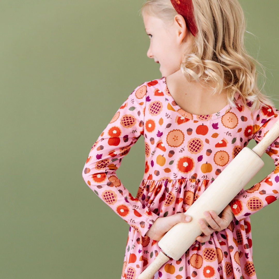 girl holding rolling pin in scoop back pumpkin pie print harvest dress 