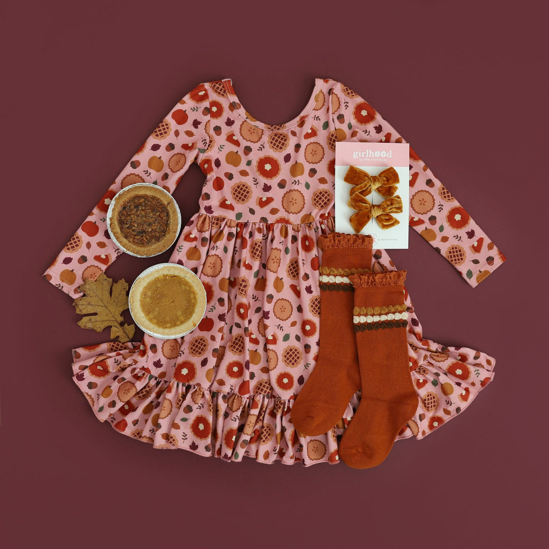 styled photo of girls Thanksgiving dress with pumpkin pie print and matching harvest knee highs and velvet pigtail bows