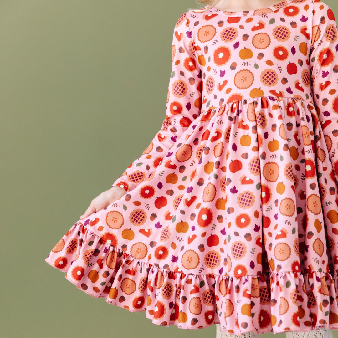 detail photo of girls pink fall dress with pumpkin pies, fall leaves and acorns