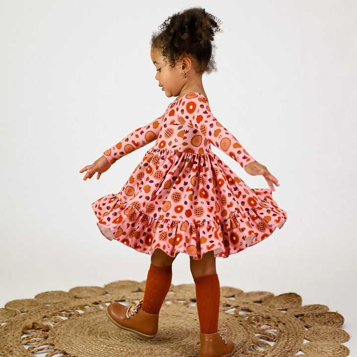 little girl twirling in Thanksgiving dress with pumpkin and apple pie print and matching pumpkin spice knee highs