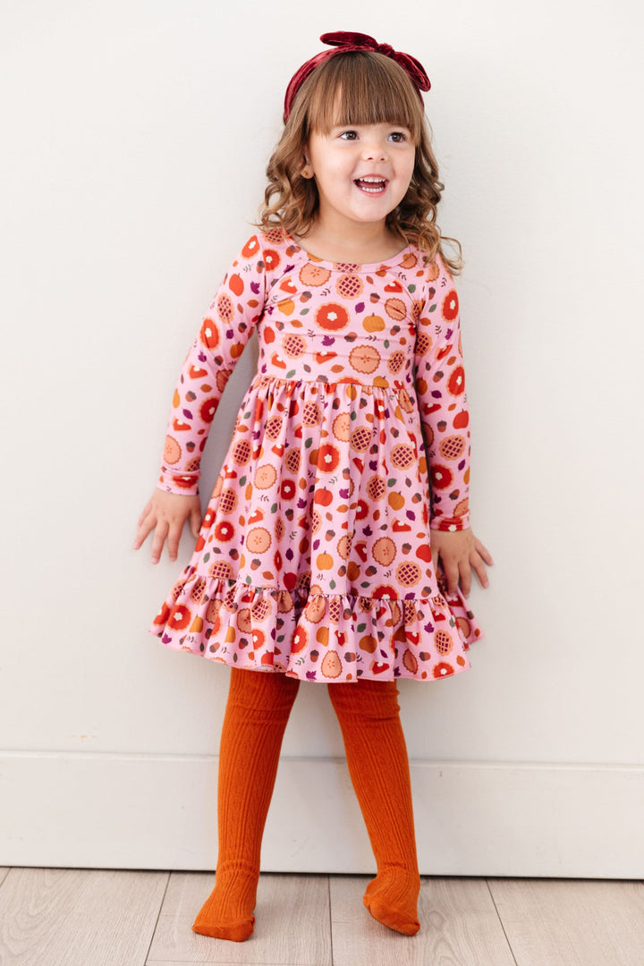 little girl in pink Thanksgiving pie dress with matching orange cable knit tights and burgundy velvet headband