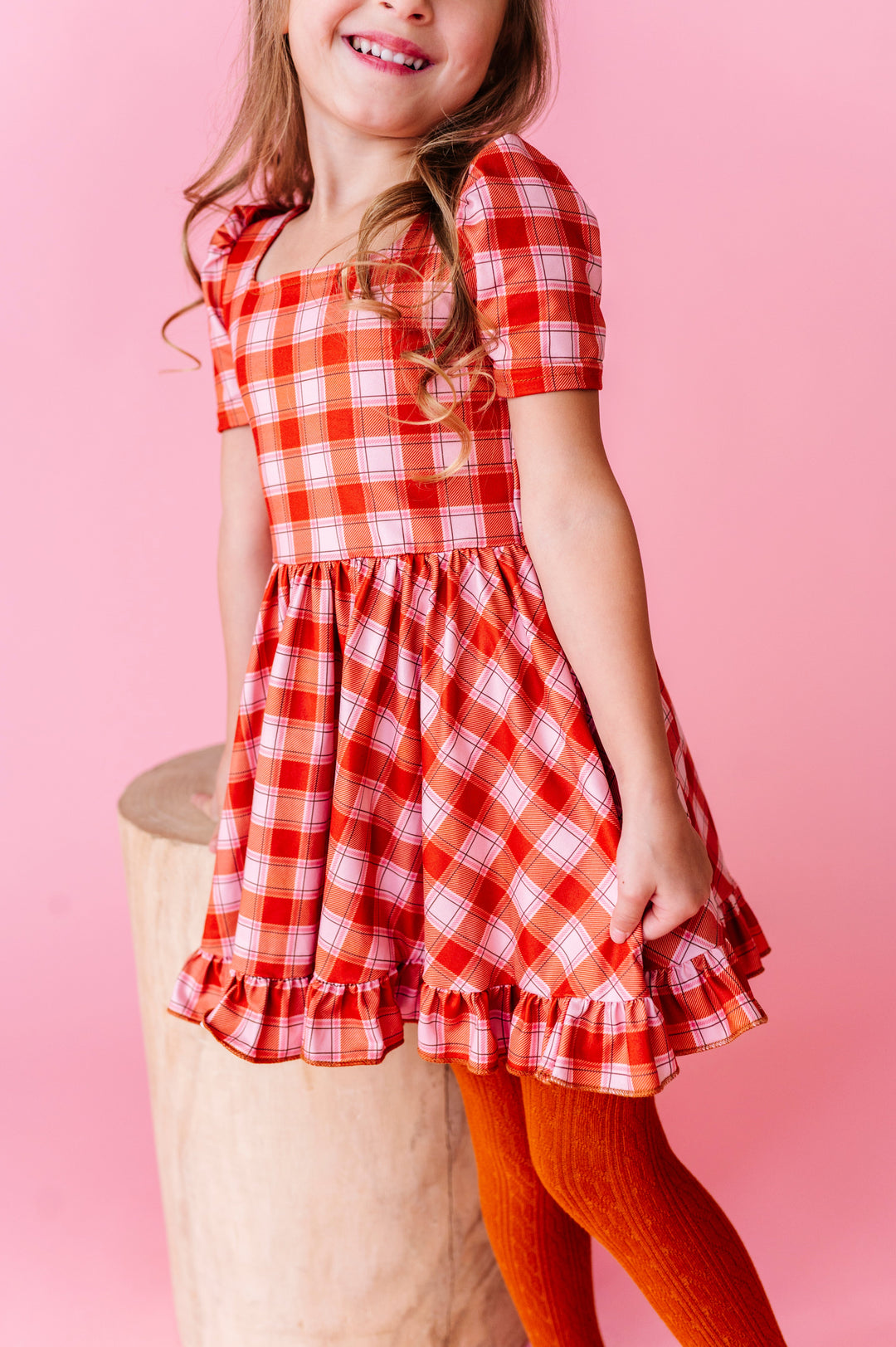 little girl in pumpkin orange plaid twirl dress paired with matching orange cable knit tights