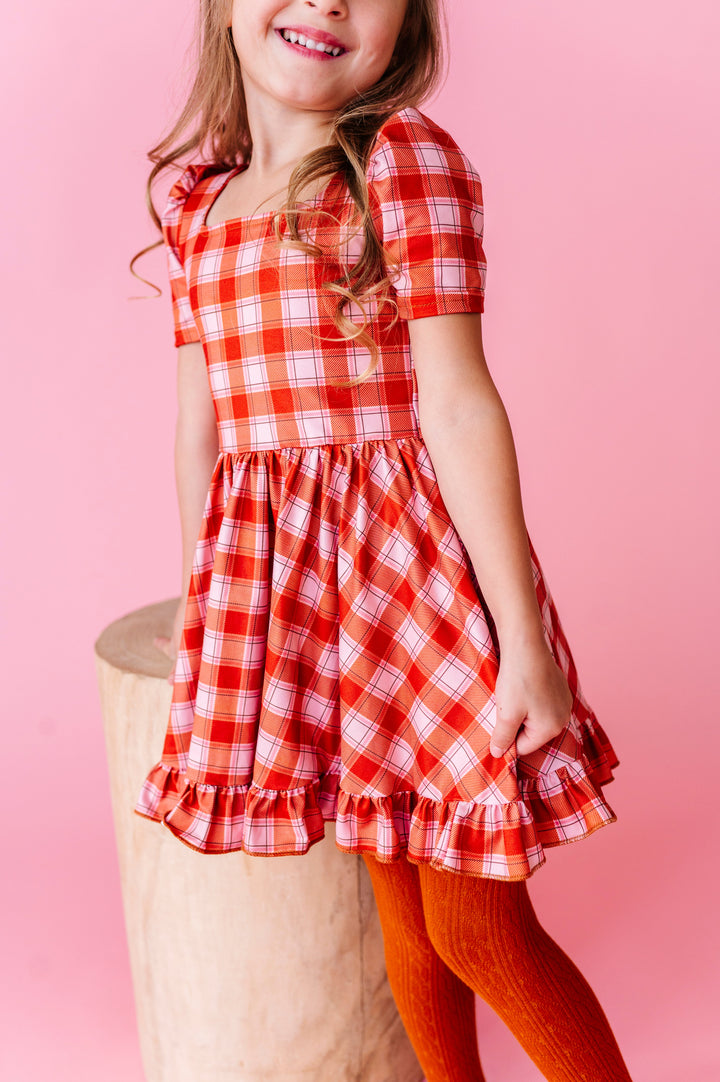 little girl in pumpkin orange plaid twirl dress paired with matching orange cable knit tights