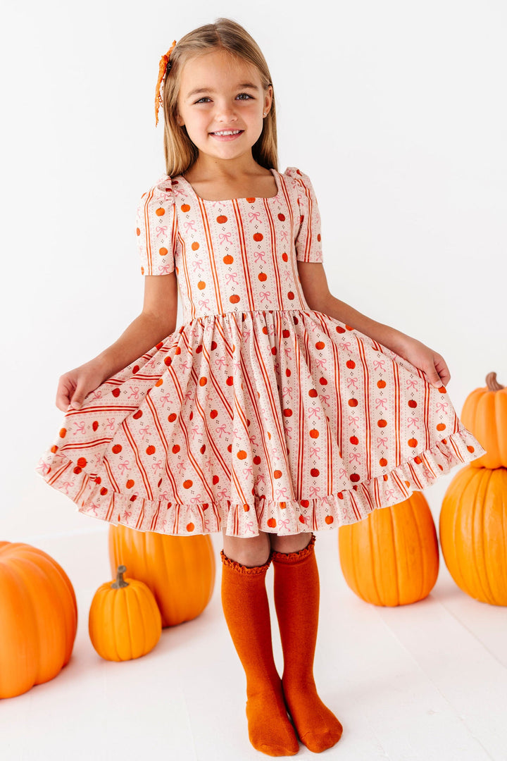 girl wearing dress with wallpaper inspired pumpkin print and matching orange knee high socks