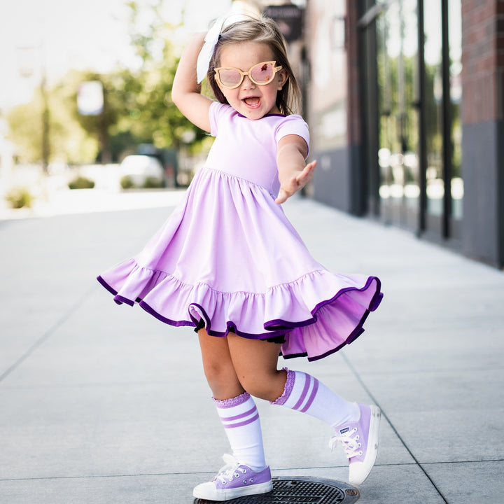 little girl twirling in light and dark purple twirl dress with matching white and purple knee high socks