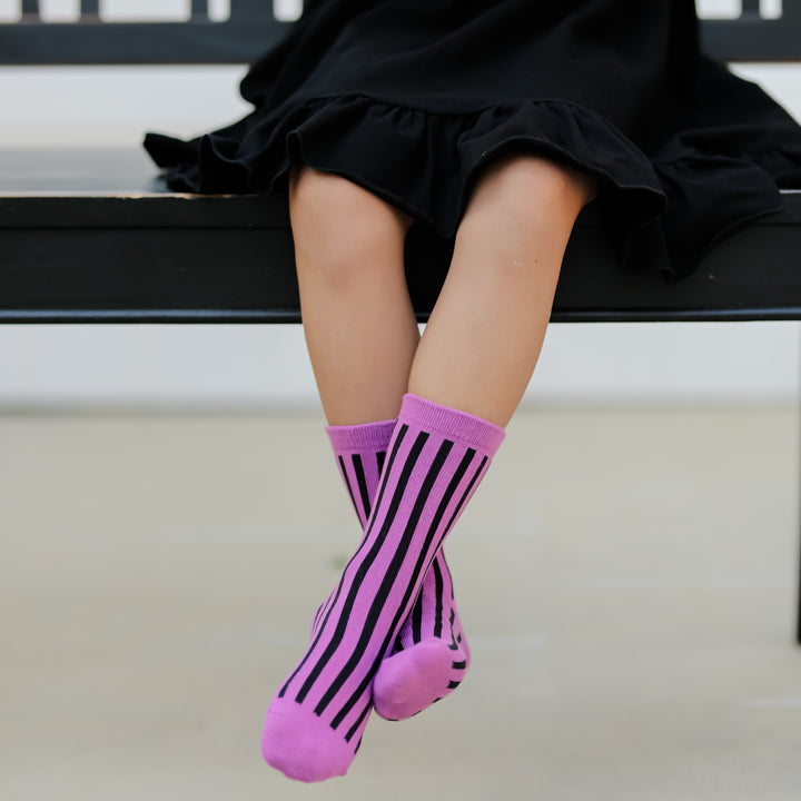 little girl wearing neon purple striped midi halloween socks